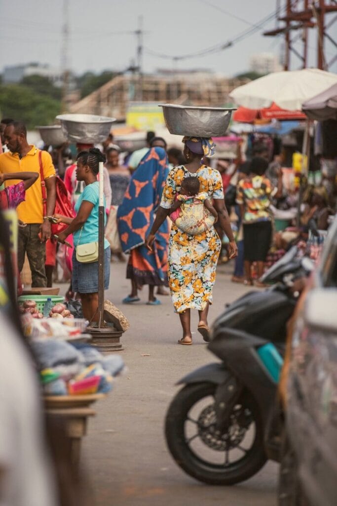 Home 19 a woman walking down a street with a bucket on her head